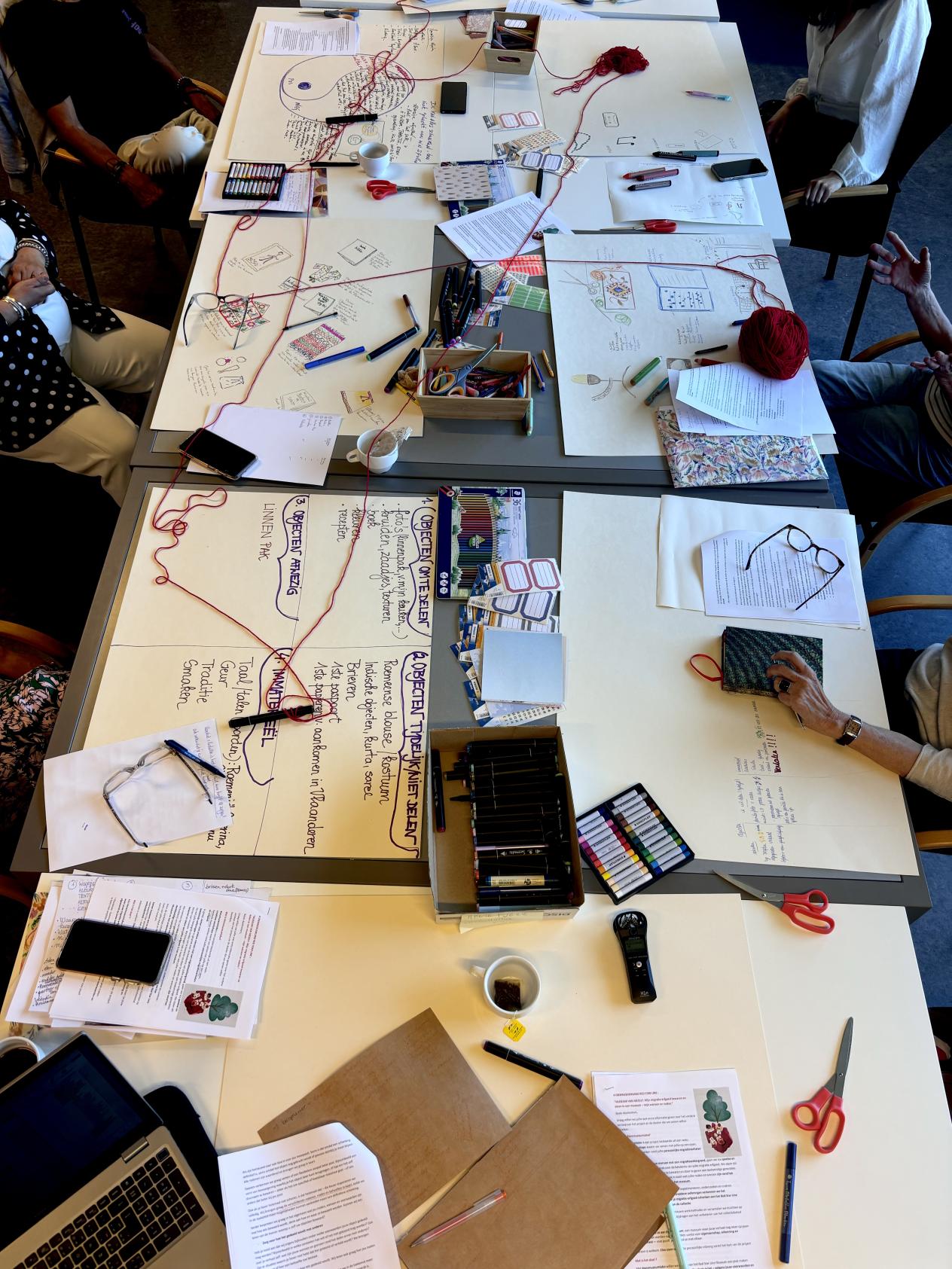 Een tafel met bladen papier en bollen wol