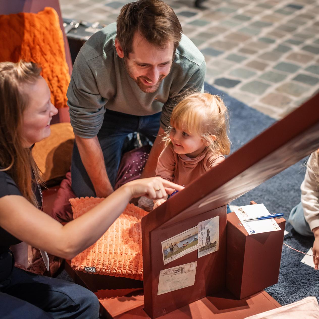 Twee volwassenen en een kleuter bekijken iets in de expo