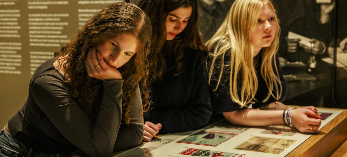 Drie meisjes leunen op een bank in het museum