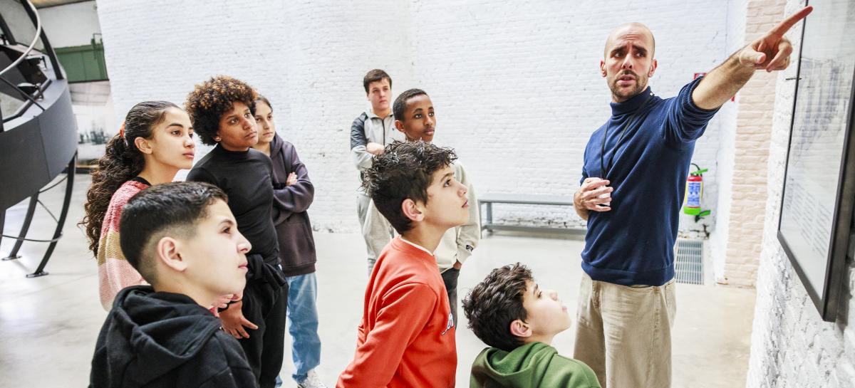 Een groep kinderen luistert naar een gids in het museum