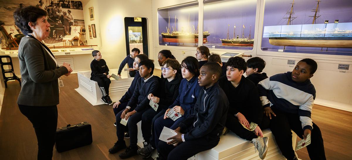 Een klas luistert naar een gids in de museumzaal