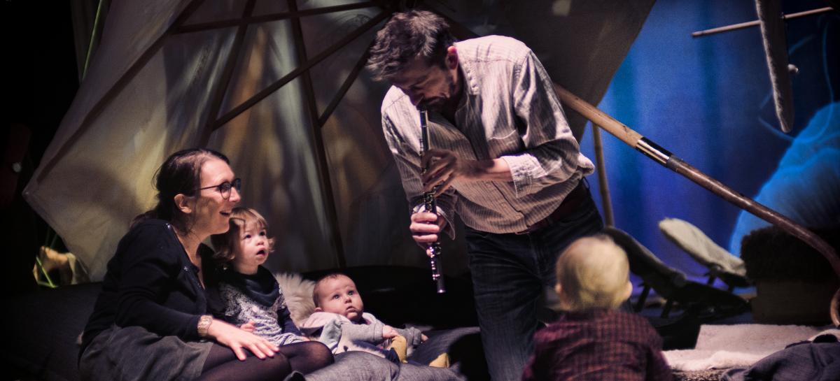Een man maakt muziek en kinderen en volwassenen luisteren toe