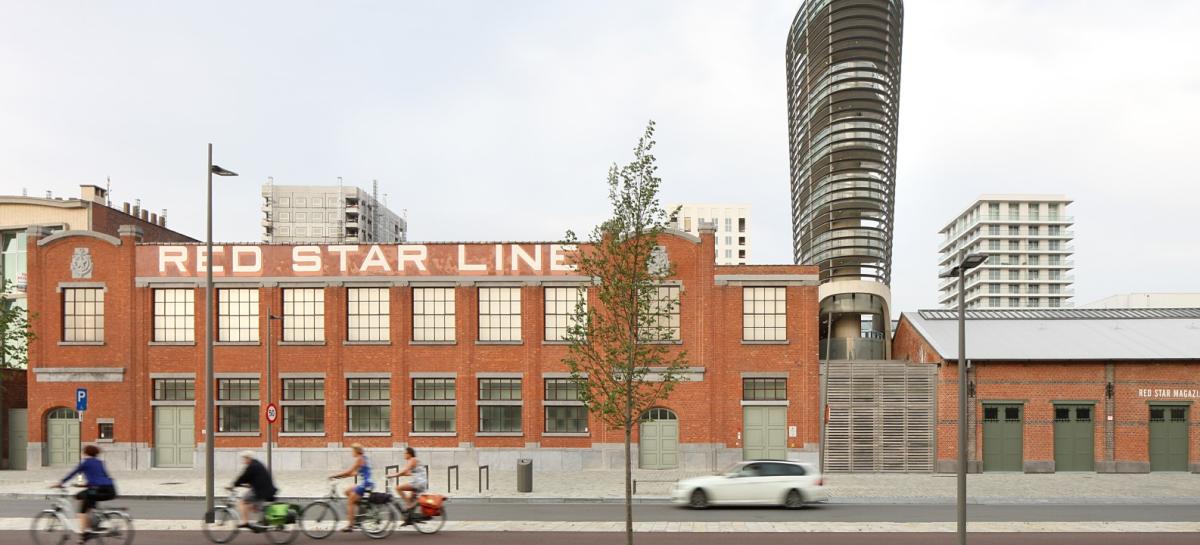 rood bakstenen gebouw met opschrift Red Star Line, een auto en fietsers die voorbij rijden