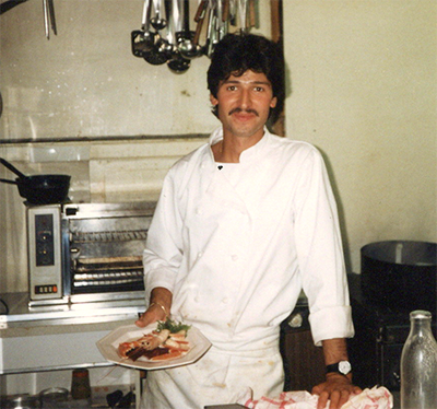 Foto van een man in kokskledij met een bord in zijn hand