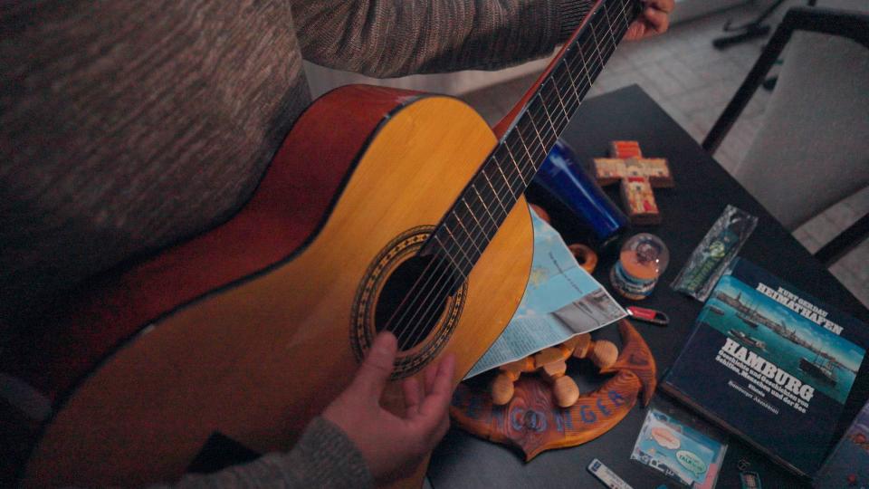 Een close-up van een gitaar waarop gespeeld wordt.