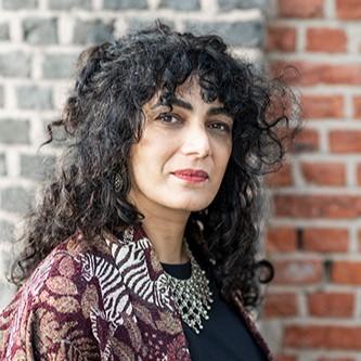 Portret van een vrouw met zwarte krullen tegen een muur