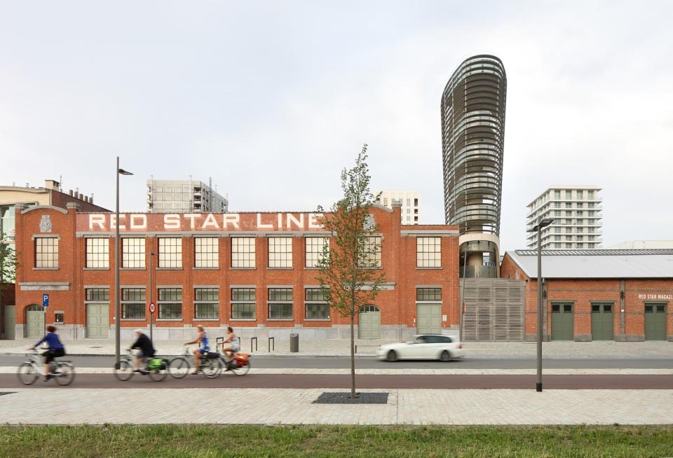 rood bakstenen gebouw met opschrift Red Star Line, een auto en fietsers die voorbij rijden