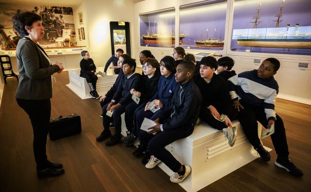 Een klas luistert naar een gids in de museumzaal