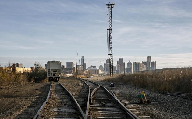 Twee treinsporen met in de verte een stilstaande trein en een toren