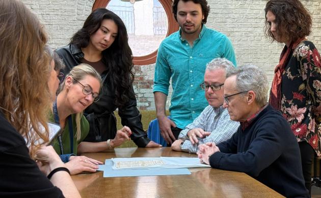 mensen zitten aan een tafel en kijken naar een document