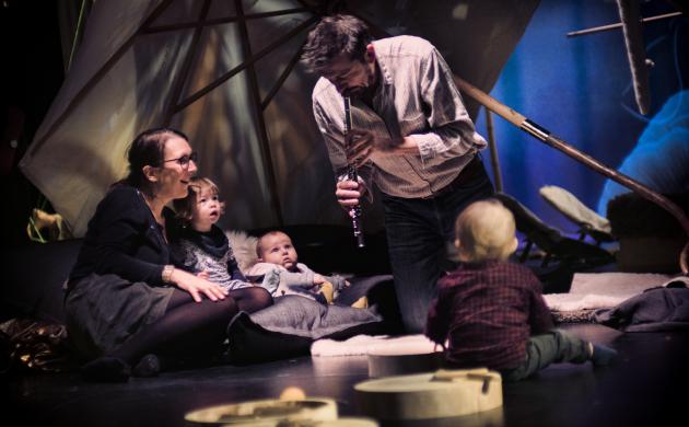 Een man maakt muziek en kinderen en volwassenen luisteren toe