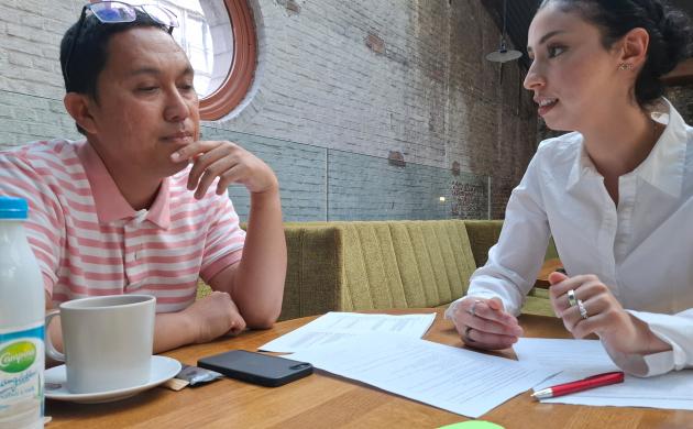 Twee mensen praten met elkaar aan een tafel