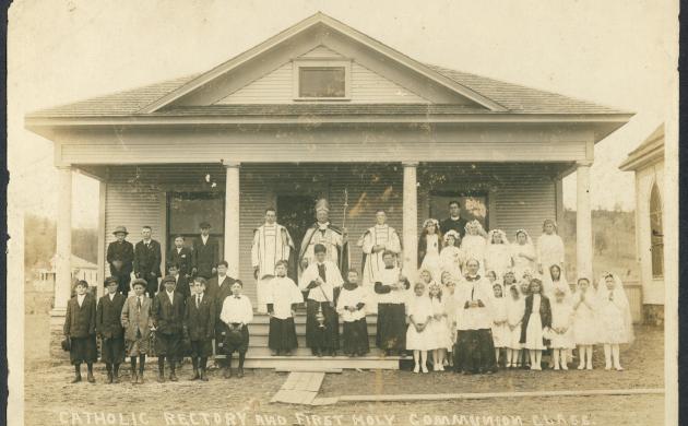 Zwart/wit foto van een huis waar een groep mensen voor staan