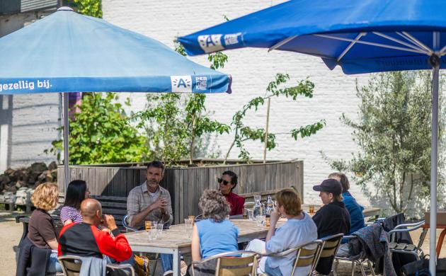 een groep mensen zit rond een tafel op een terras