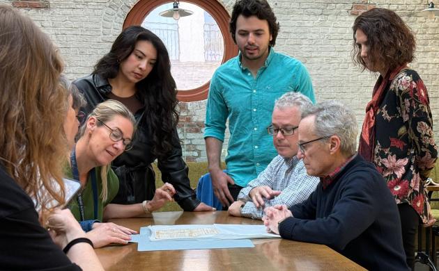 mensen zitten aan een tafel en kijken naar een document