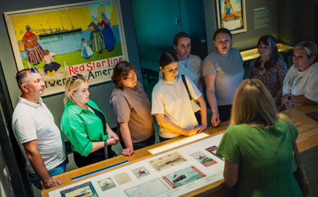 Een groep mensen luistert naar een gids in een museumzaal