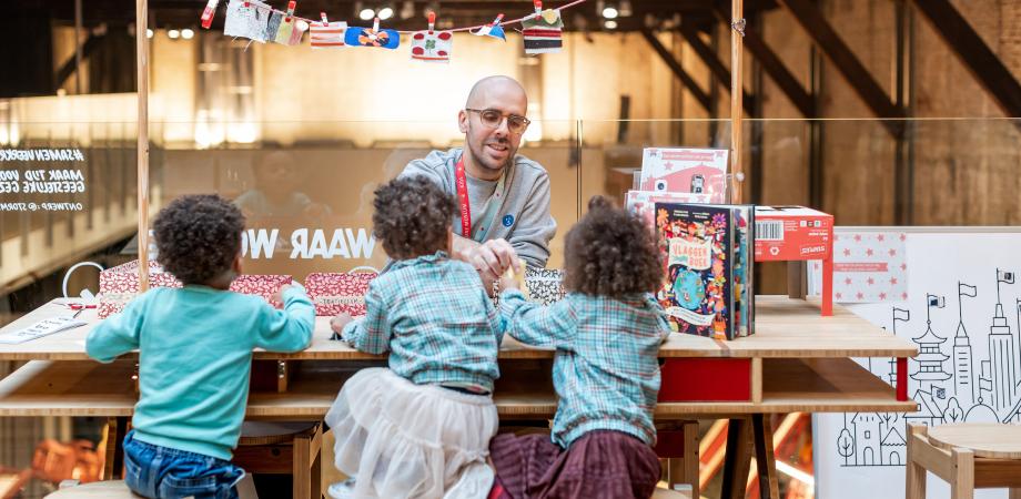 Drie kinderen en een volwassene knutselen aan een tafel