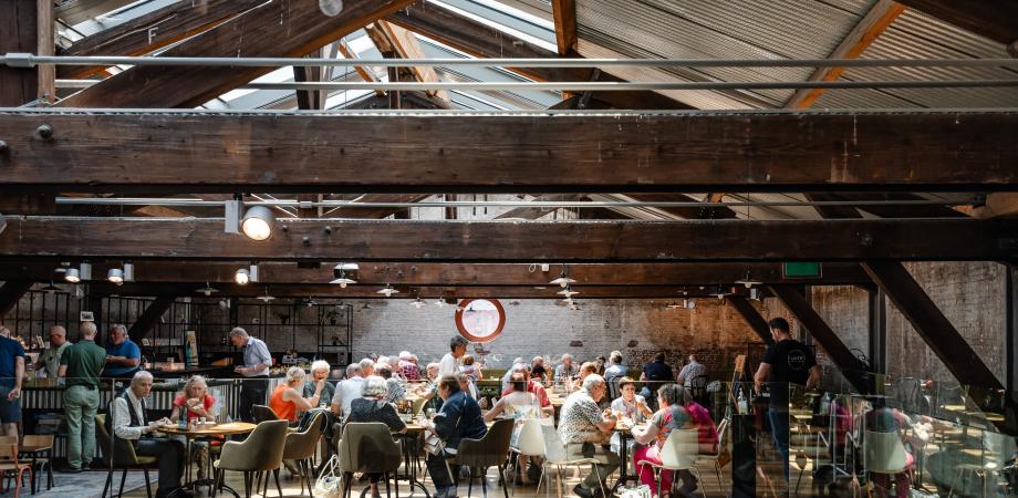 Een groep mensen zit aan tafels en eet 