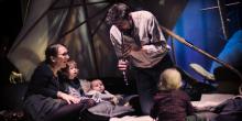 Een man maakt muziek en kinderen en volwassenen luisteren toe