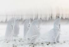 Foto van figuren met een wit kleed in een sneeuwlandschap