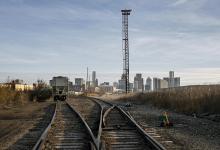 Twee treinsporen met in de verte een stilstaande trein en een toren