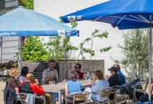 een groep mensen zit rond een tafel op een terras