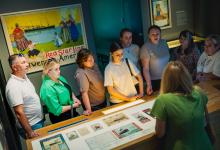 Een groep mensen luistert naar een gids in een museumzaal